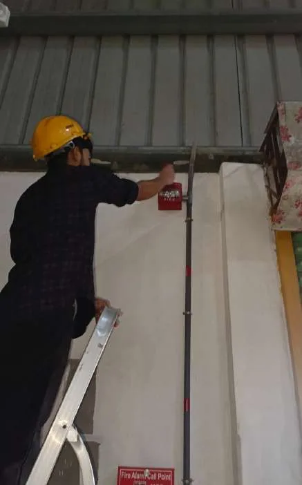 Technician installing a fire alarm call point