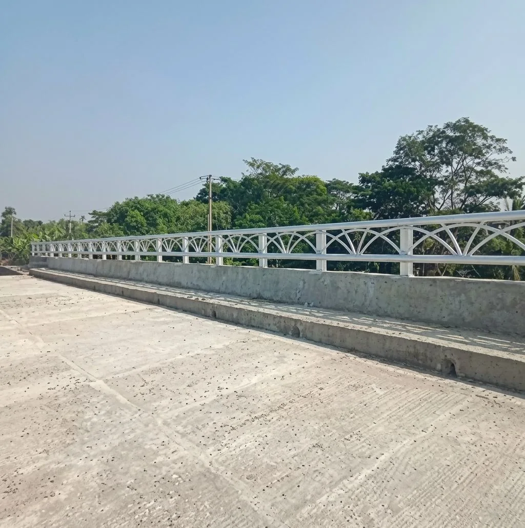 Metal bridge railing beside a paved roadway